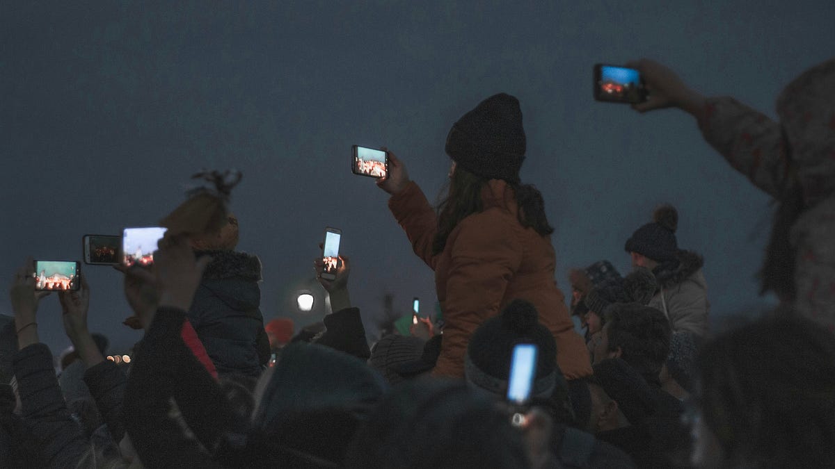Multitud observando pantallas en un entorno digital que simboliza el consenso social